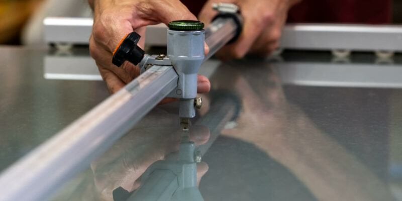 Person using a tool to cut a large pane of glass