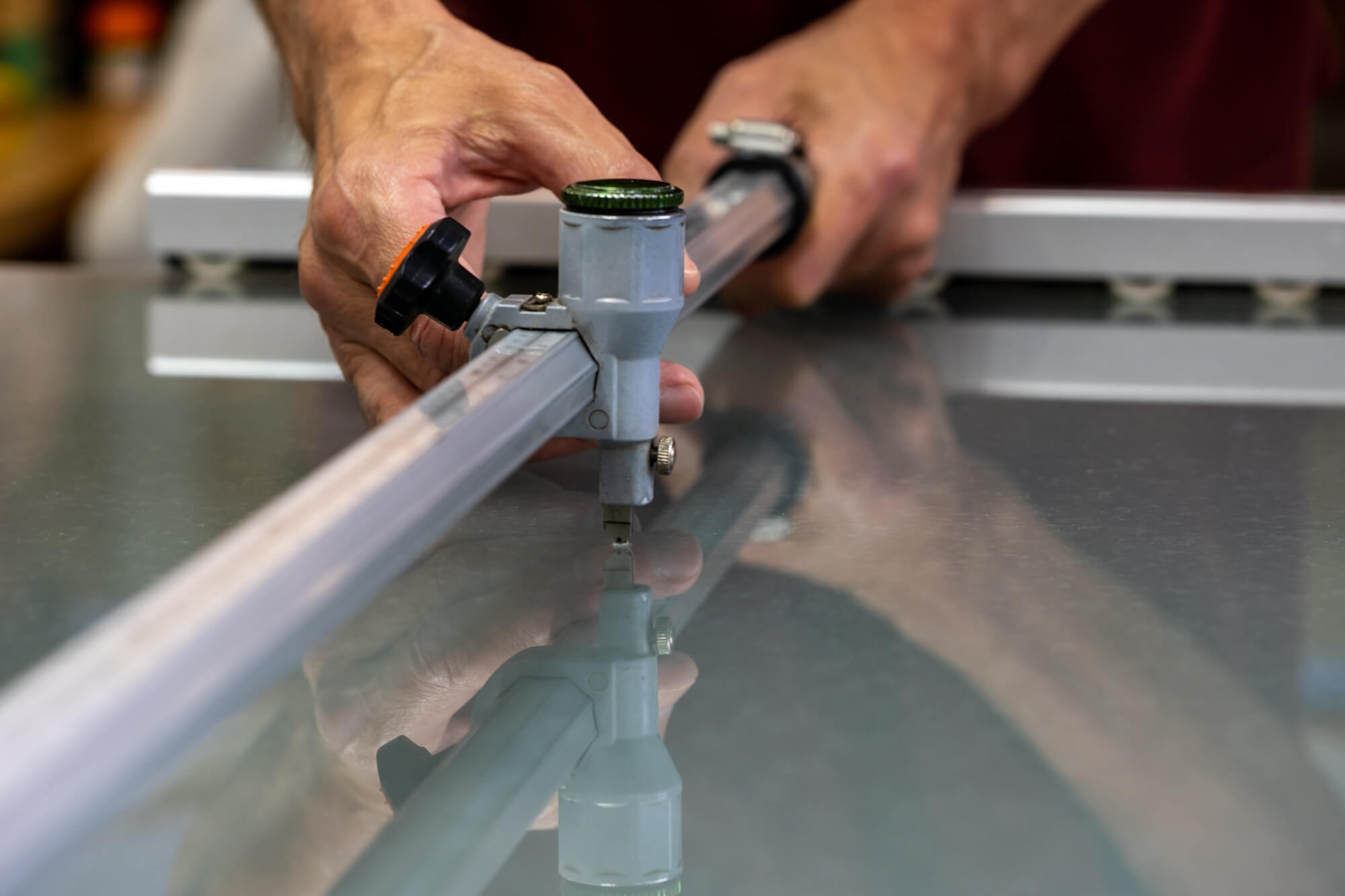 Person using a tool to cut a large pane of glass