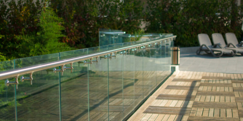 Glass balustrade with chrome handrail set around wooden decking.