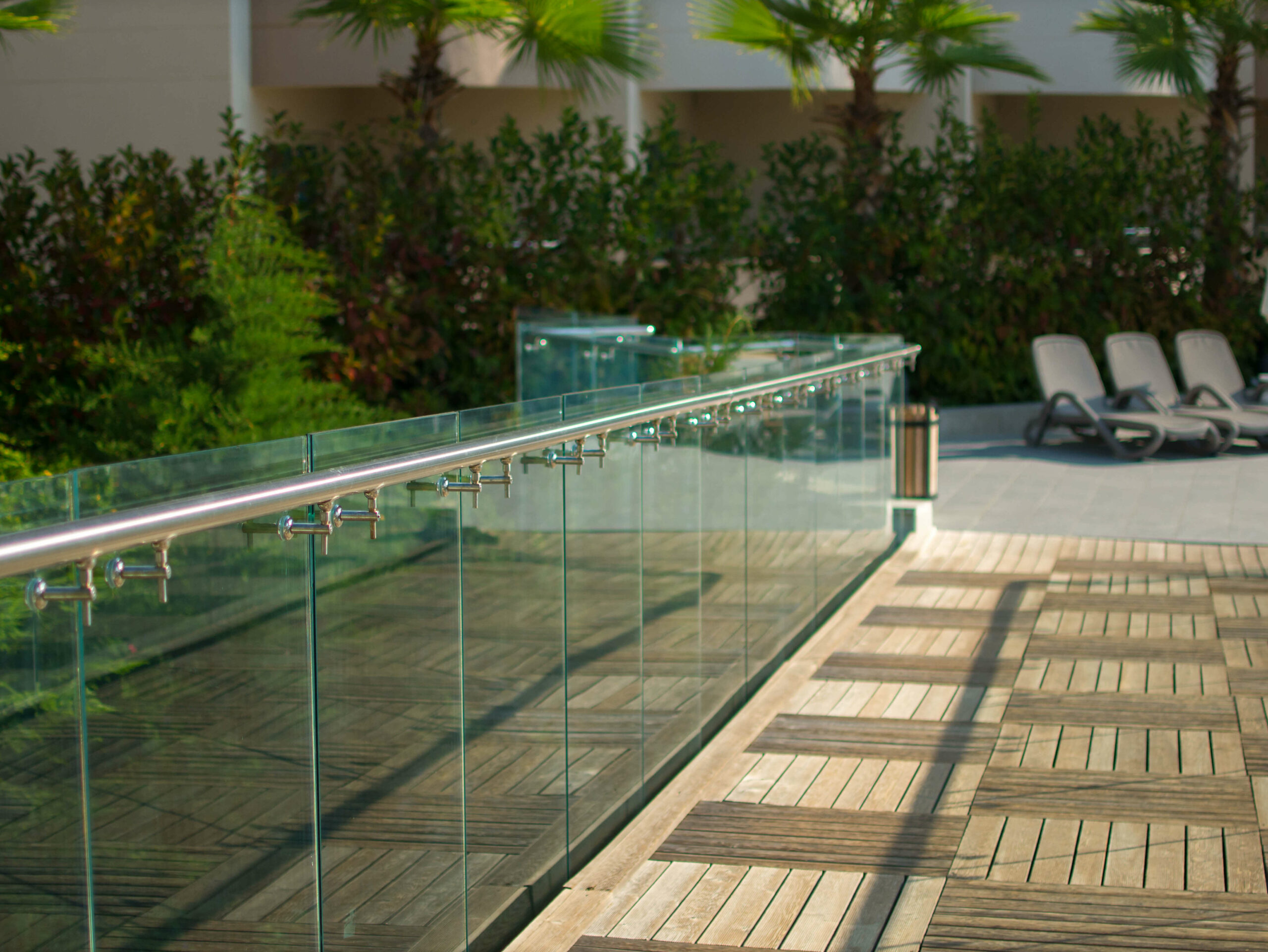 Glass balustrade with chrome handrail set around wooden decking.